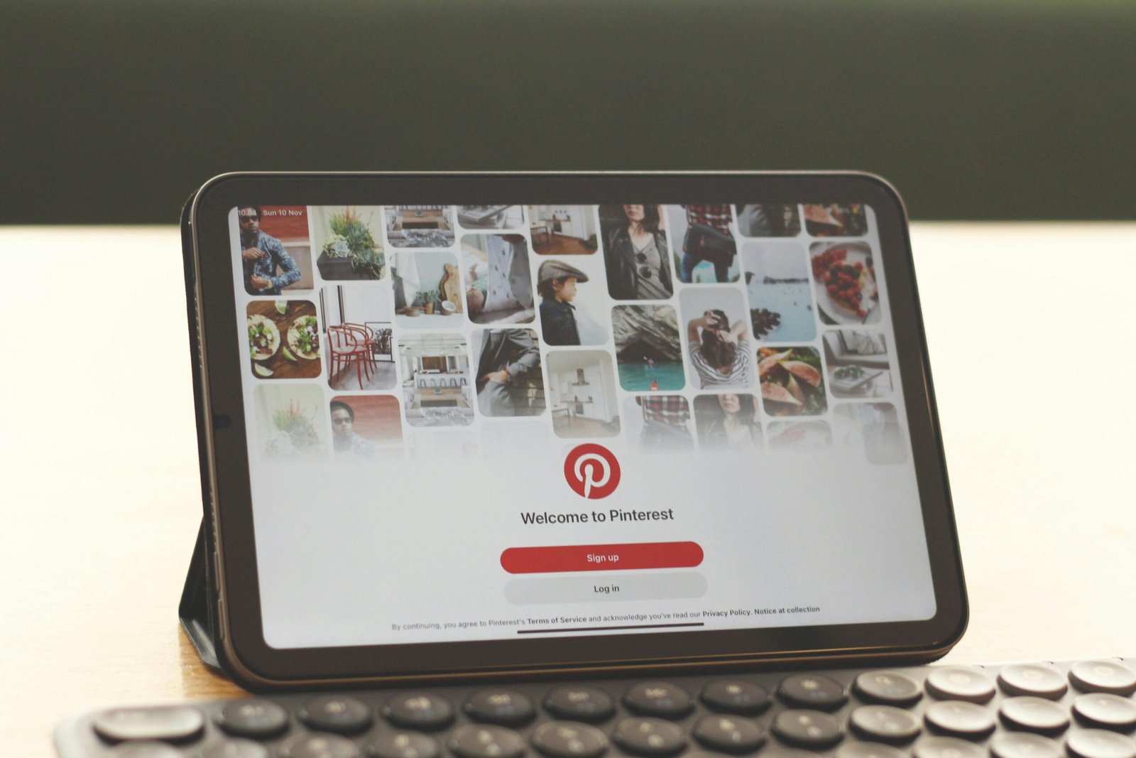 Tablet showing Pinterest homepage on a modern desk setup with a keyboard.