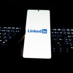 Close-up of LinkedIn logo on smartphone with backlit keyboard in dark room.