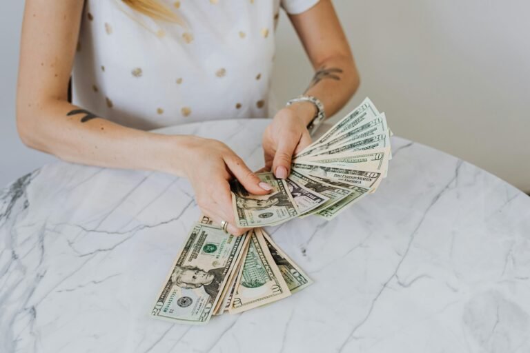 Close-up of a person counting US dollar bills on a luxurious marble table, symbolizing wealth and finance.